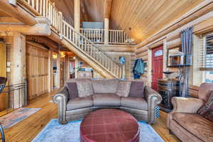 Living room with hardwood / wood-style floors, wood ceiling, high vaulted ceiling, and log walls