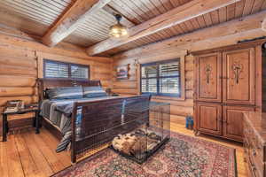 Bedroom featuring rustic walls, light hardwood / wood-style floors, wooden ceiling, and beamed ceiling