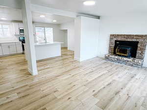 Unfurnished living room featuring a healthy amount of sunlight, sink, and light wood-type flooring