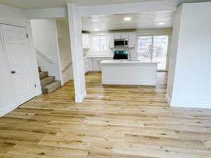 Kitchen featuring white cabinetry, sink, light hardwood / wood-style flooring, and range with electric stovetop