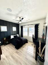 Bedroom featuring ceiling fan, a textured ceiling, and light wood-type flooring