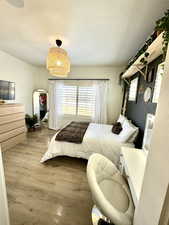 Bedroom with a textured ceiling, multiple windows, and light wood-type flooring