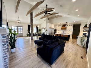 Living room featuring vaulted ceiling with beams, light hardwood / wood-style flooring, sink, and a textured ceiling