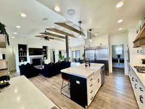 Kitchen featuring hanging light fixtures, light hardwood / wood-style floors, an island with sink, and white cabinets