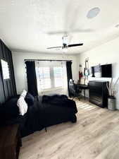 Bedroom with a textured ceiling, light hardwood / wood-style floors, and ceiling fan