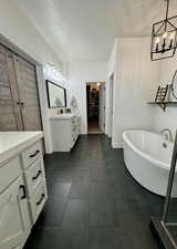 Bathroom with vanity, a textured ceiling, and a bathtub