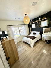 Bedroom with hardwood / wood-style flooring, multiple windows, and a textured ceiling