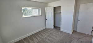 Unfurnished bedroom with light colored carpet and a closet