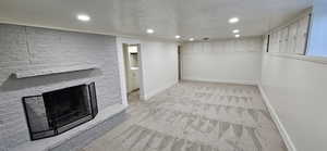 Unfurnished living room featuring a brick fireplace, light colored carpet, and a textured ceiling