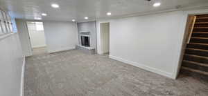 Basement with a brick fireplace, light carpet, and a textured ceiling