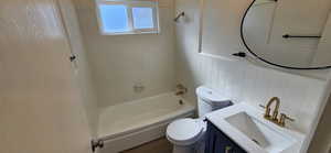 Full bathroom featuring tiled shower / bath combo, vanity, tile walls, and toilet