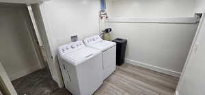 Laundry room with light hardwood / wood-style flooring and washer and clothes dryer