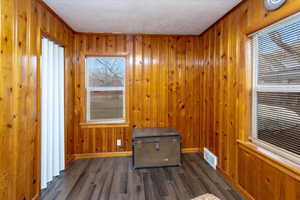 Interior space with plenty of natural light, dark hardwood / wood-style flooring, and wood walls