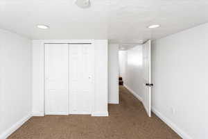 Unfurnished bedroom with carpet floors, a closet, and a textured ceiling