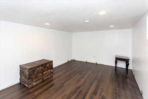 Empty room featuring dark wood-type flooring and a textured ceiling