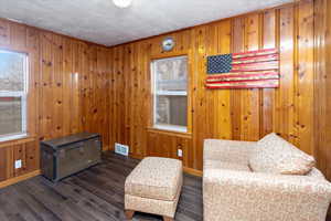 Sitting room featuring dark hardwood / wood-style floors, a textured ceiling, and wood walls