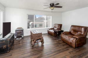 Sitting room featuring dark hardwood / wood-style flooring, ceiling fan, and a wood stove