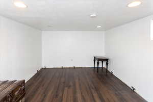 Unfurnished room featuring dark hardwood / wood-style flooring and a textured ceiling