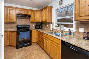 Kitchen featuring sink, backsplash, black appliances, light stone countertops, and light tile patterned flooring