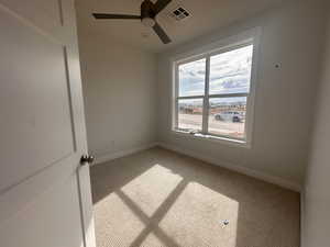 Spare room featuring light carpet, ceiling fan, and plenty of natural light