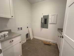 Laundry room with electric dryer hookup, cabinet space, electric panel, washer hookup, and dark tile patterned flooring