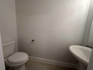 Half bathroom featuring baseboards and toilet