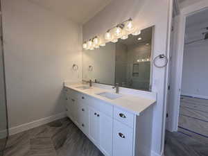 Bathroom featuring double vanity and a marble finish shower