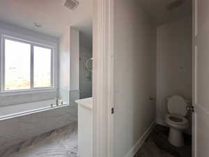 Bathroom featuring marble finish flooring and tiled tub