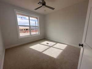 Carpeted empty room featuring a ceiling fan and baseboards