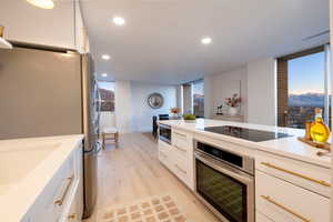 Kitchen featuring stainless steel appliances, white cabinetry, expansive windows, and light wood-type flooring