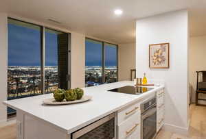 Kitchen featuring black electric stovetop, beverage cooler, oven, light hardwood / wood-style floors, and white cabinets