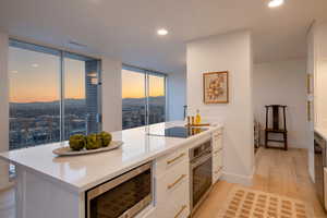 Kitchen featuring white cabinetry, appliances with stainless steel finishes, floor to ceiling windows, and light wood-type flooring