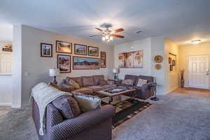 Carpeted living room with ceiling fan