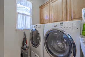 Clothes washing area featuring cabinets and washer and dryer