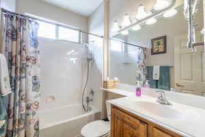 Full bathroom with vanity, shower / bath combination with curtain, and toilet