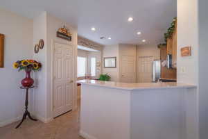 Kitchen with appliances with stainless steel finishes, kitchen peninsula, and light tile patterned floors