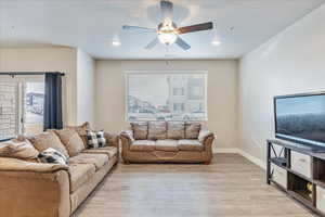 Living room featuring ceiling fan and light hardwood / wood-style flooring