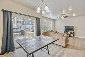 Dining area featuring ceiling fan with notable chandelier and light wood-type flooring