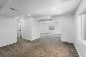 Empty room with carpet floors, baseboards, visible vents, and recessed lighting