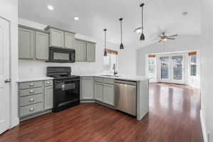 Kitchen with dark wood-style floors, light countertops, a sink, a peninsula, and black appliances