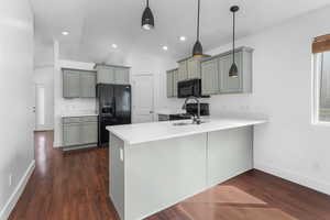 Kitchen featuring a peninsula, black appliances, dark wood-style floors, and light countertops