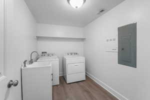 Clothes washing area featuring visible vents, separate washer and dryer, wood finished floors, laundry area, and electric panel