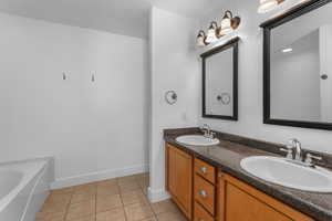 Bathroom featuring double vanity, a sink, baseboards, and tile patterned floors