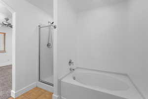 Full bath featuring ceiling fan, a garden tub, tile patterned flooring, baseboards, and a stall shower