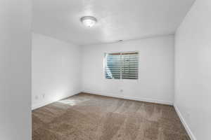 Carpeted empty room featuring baseboards and a textured ceiling