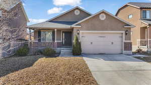 View of front of house with a garage, brick siding, fence, driveway, and stucco siding