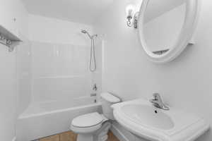 Bathroom with bathing tub / shower combination, tile patterned flooring, a sink, and toilet