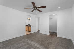 Unfurnished bedroom featuring carpet floors, baseboards, arched walkways, and a sink