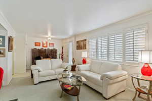 Carpeted living room with ornamental molding