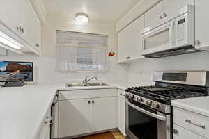 Kitchen featuring stainless steel gas range oven, ornamental molding, and white cabinets